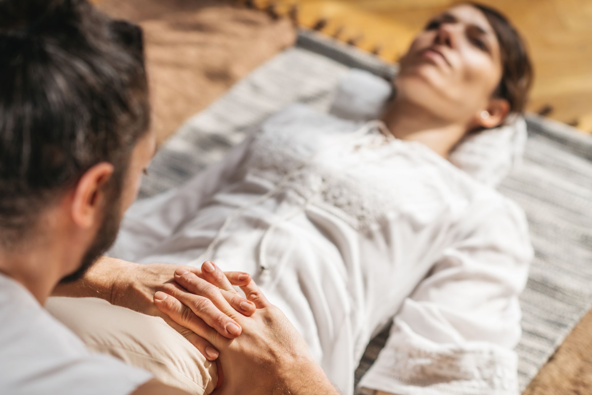 Iemand geeft een kniemassage aan een persoon die buiten ligt.