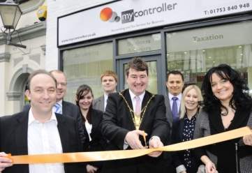 A group of people are cutting a ribbon in front of a store called my controller
