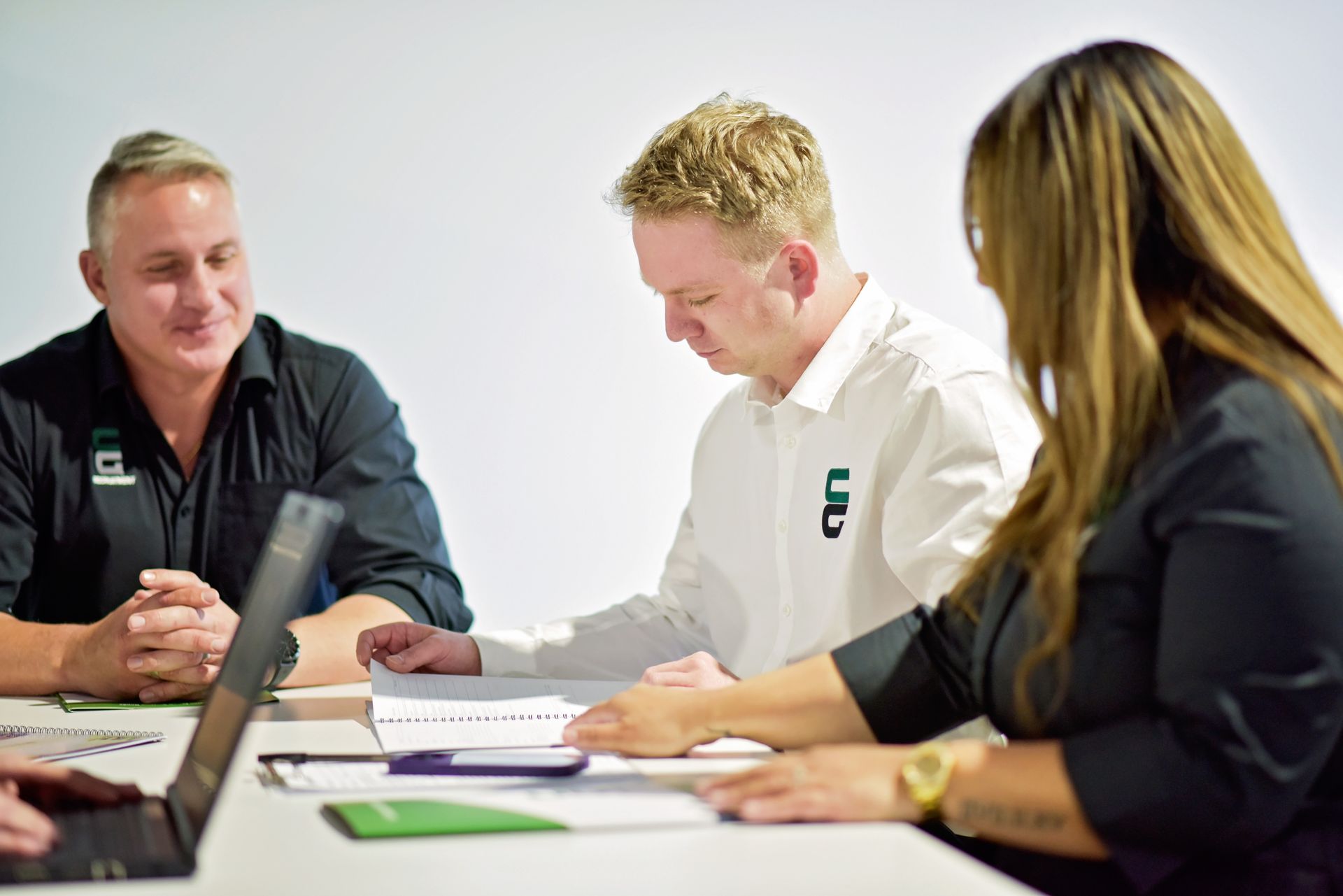 A group of people are sitting at a table with a laptop.