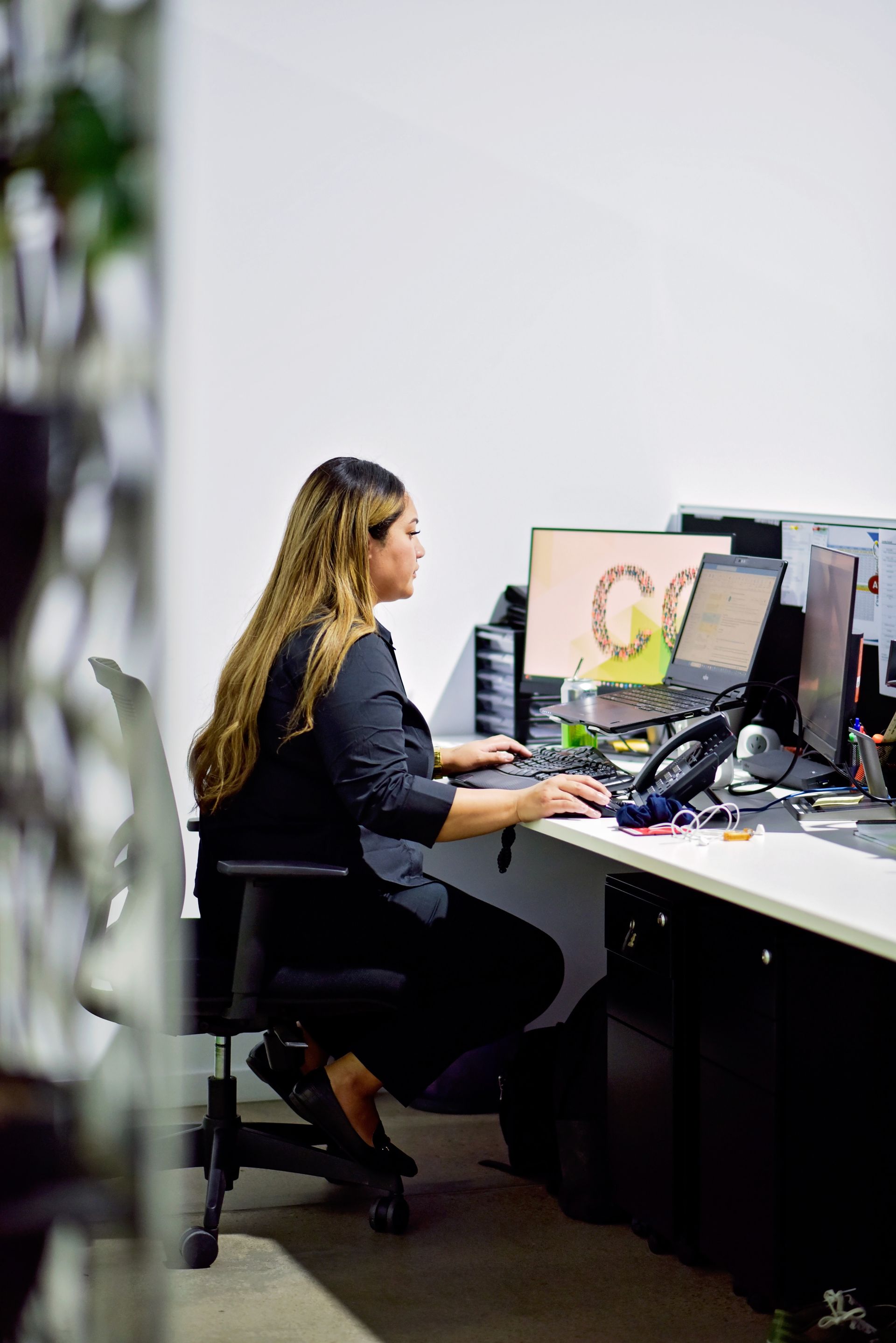A woman is sitting at a desk in front of a computer.