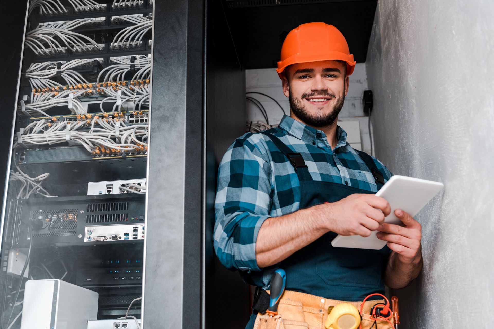 A man wearing a hard hat is holding a tablet.