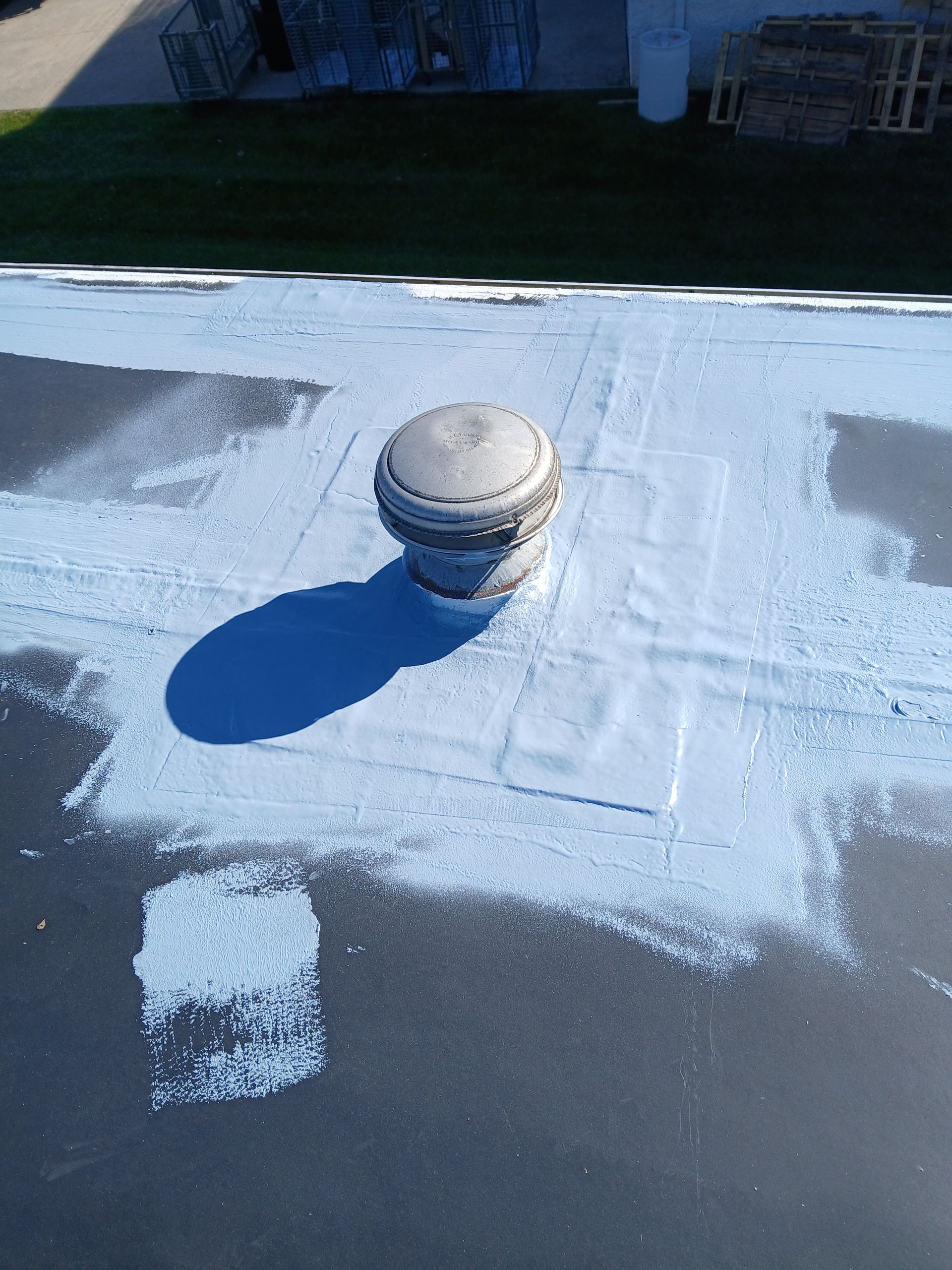 Person in blue jacket and jeans kneels, applying patch to a roof. Wearing gloves. Person in blue jacket and jeans kneels, applying patch to a roof. Wearing gloves.