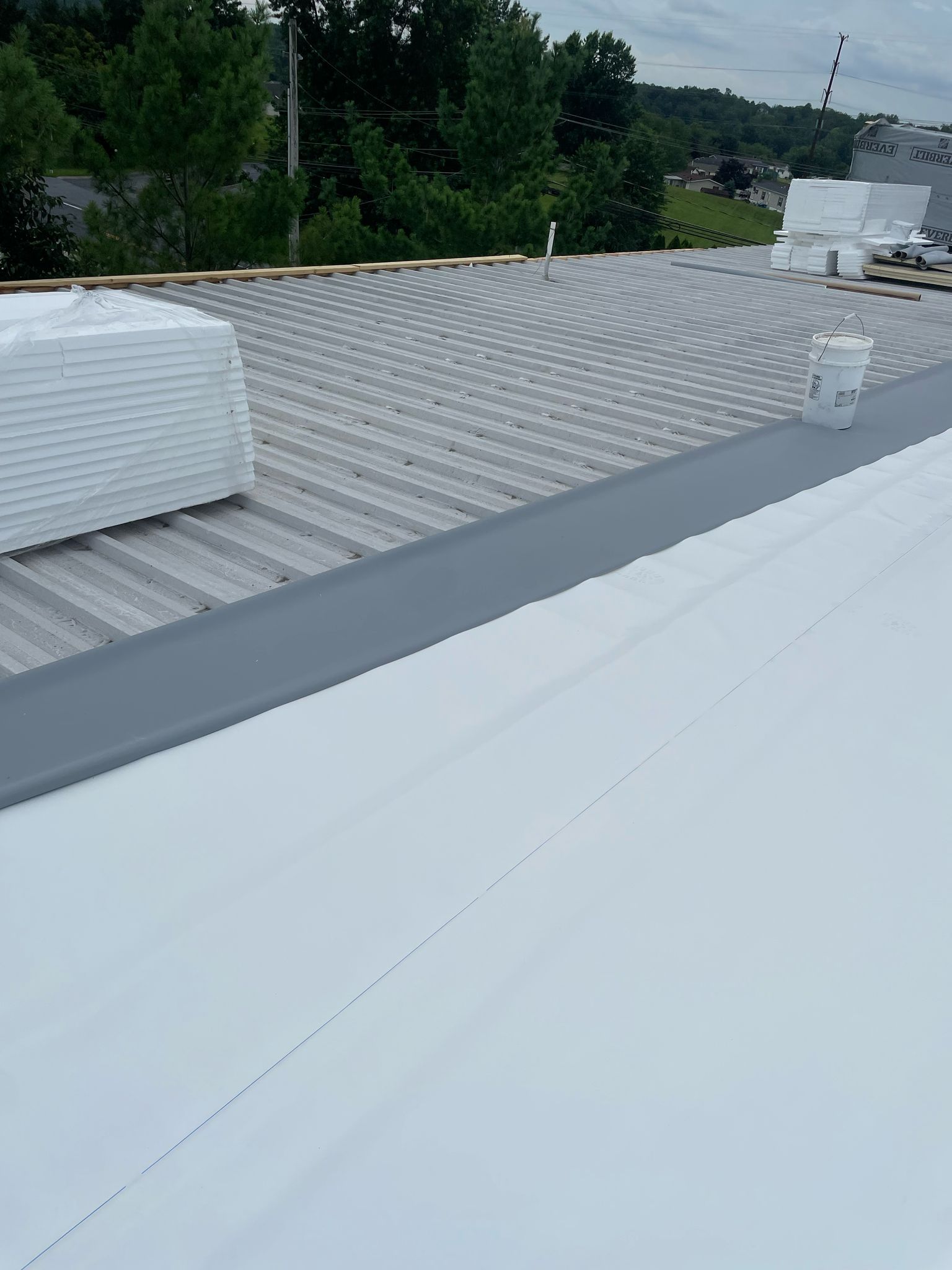 Roofer on a roof, attaching metal panels. Sunset sky background.