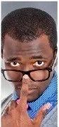 Person wearing glasses and a blue shirt, looking over the frames and touching their nose.