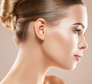 Profile of a woman with a sleek bun, looking right against a soft beige background