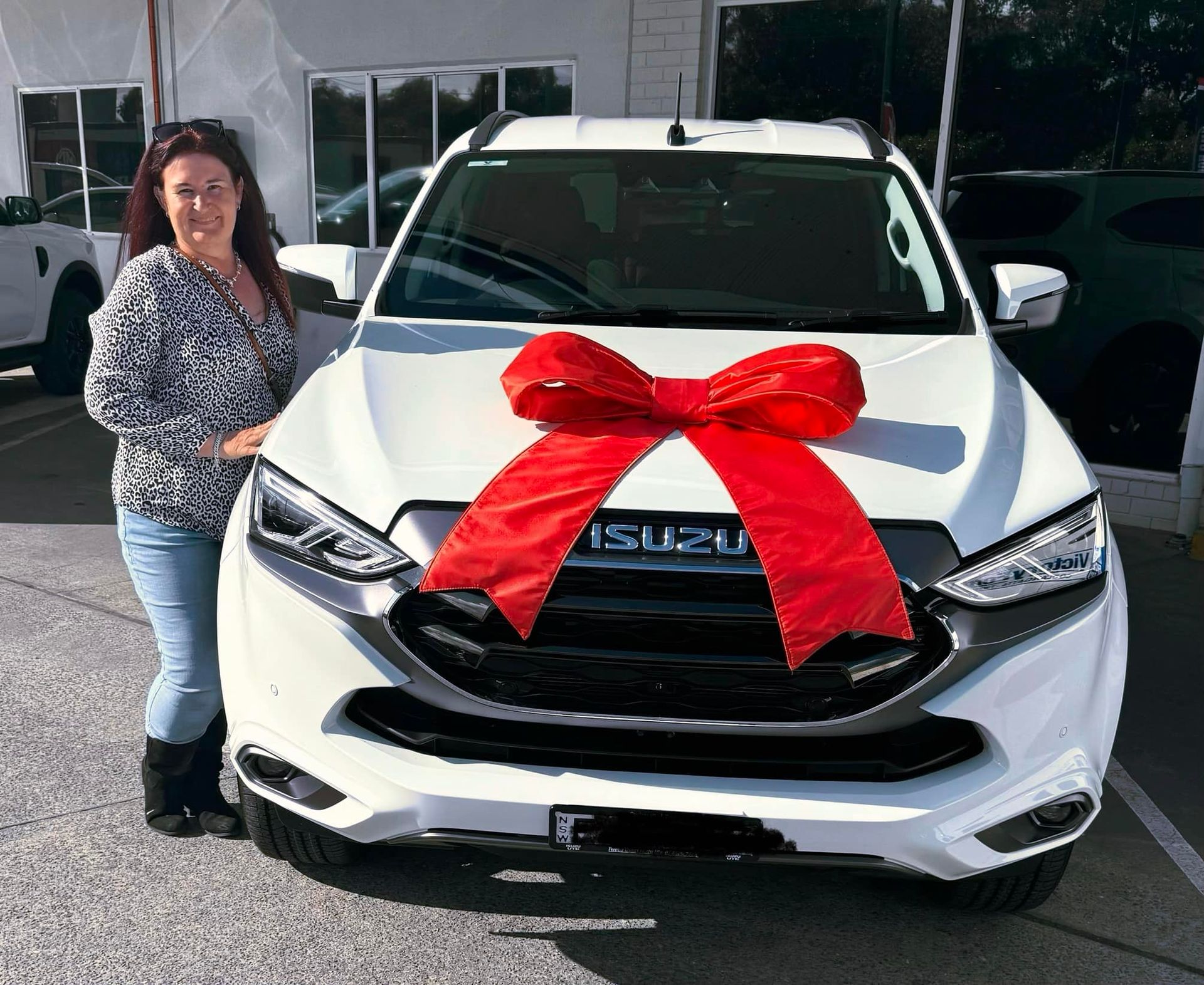 A Woman Is Standing In Front Of A White Car With A Red Bow On It — One Lane Financial In Burdell, QLD