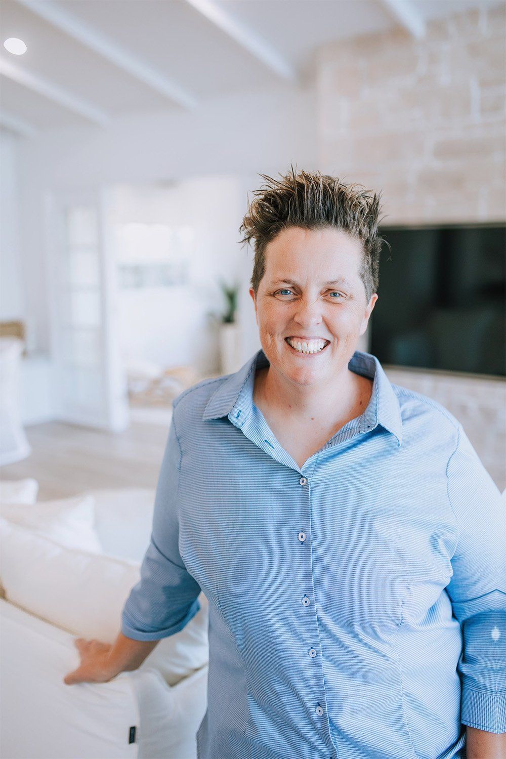 A Woman In A Blue Shirt Is Standing In A Living Room And Smiling — One Lane Financial In Burdell, QLD
