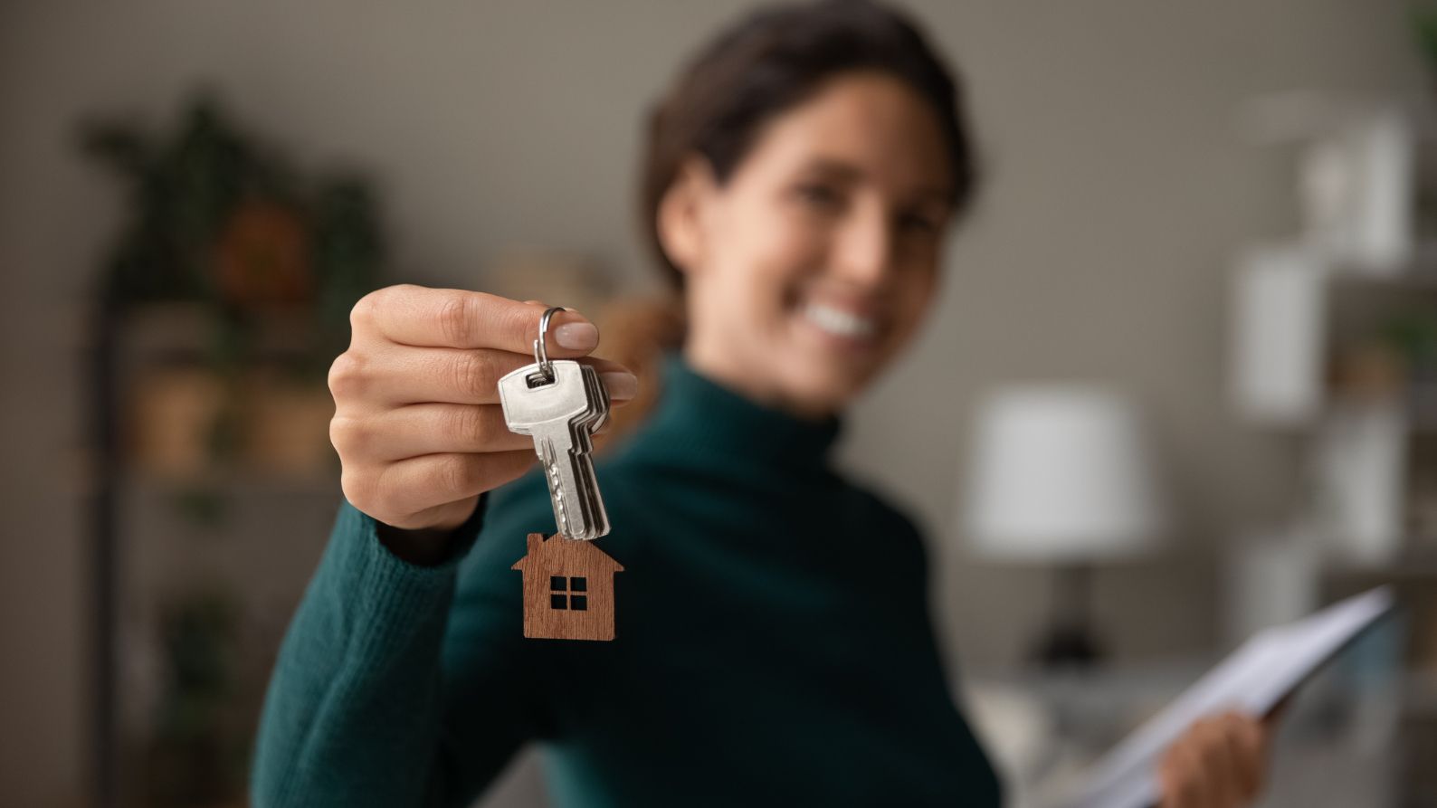 A Woman Is Holding A Key With A House Keychain On It — One Lane Financial In Burdell, QLD