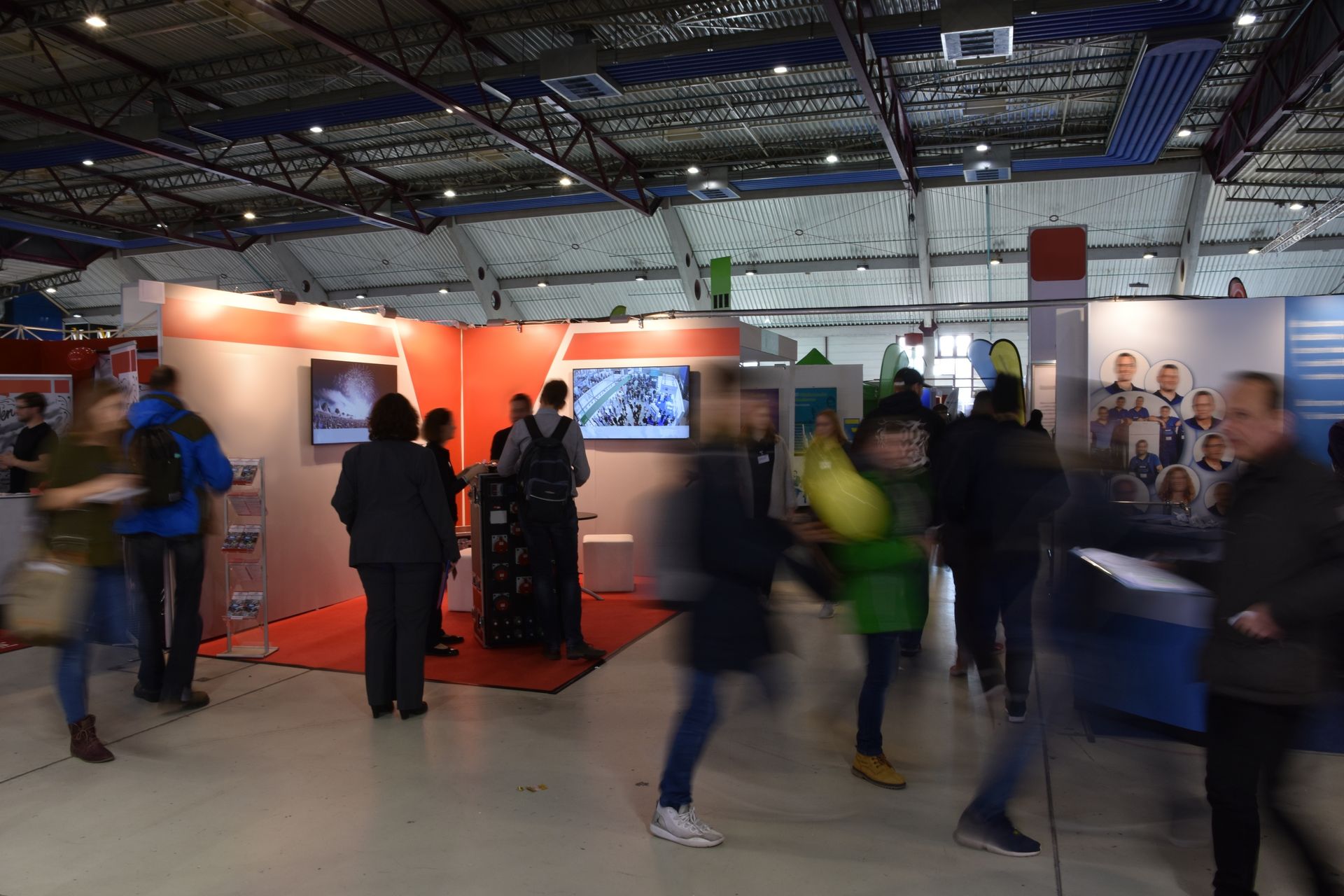 People walking through an exhibition hall featuring a large screen displaying visuals.