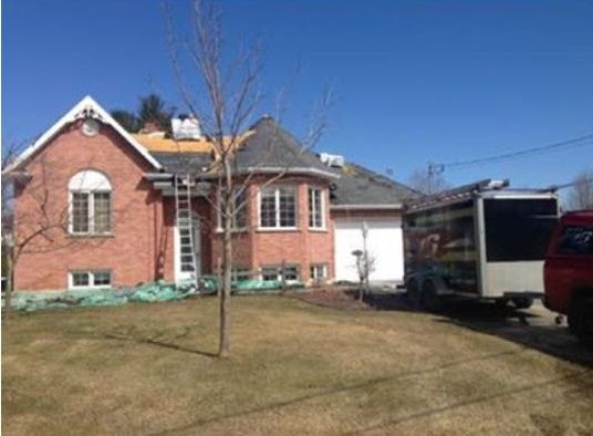 Un camion rouge est garé devant une maison en brique