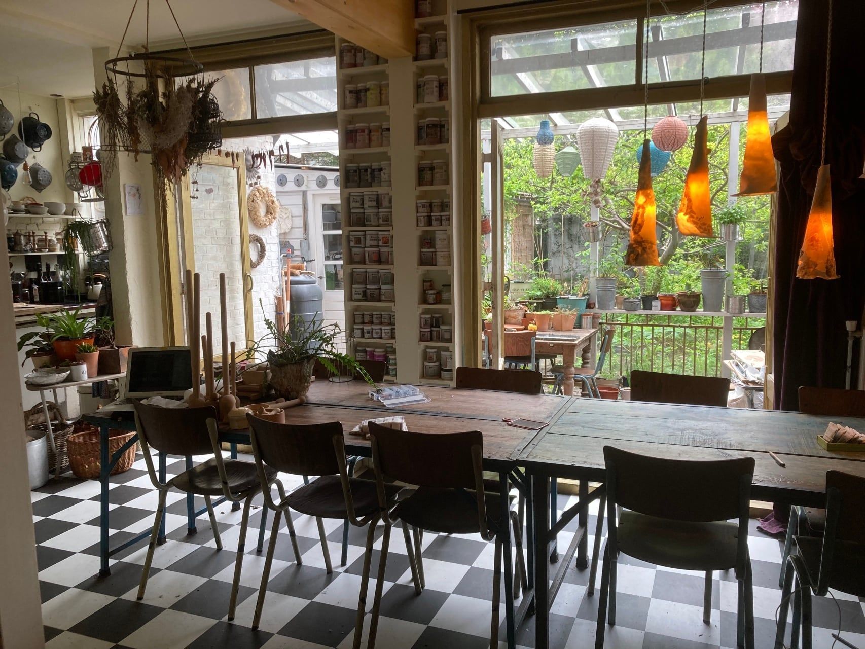 atelierruimte in den haag met stoelen rondom lange tafel. uitzicht op de keuken en het groen van de tuin