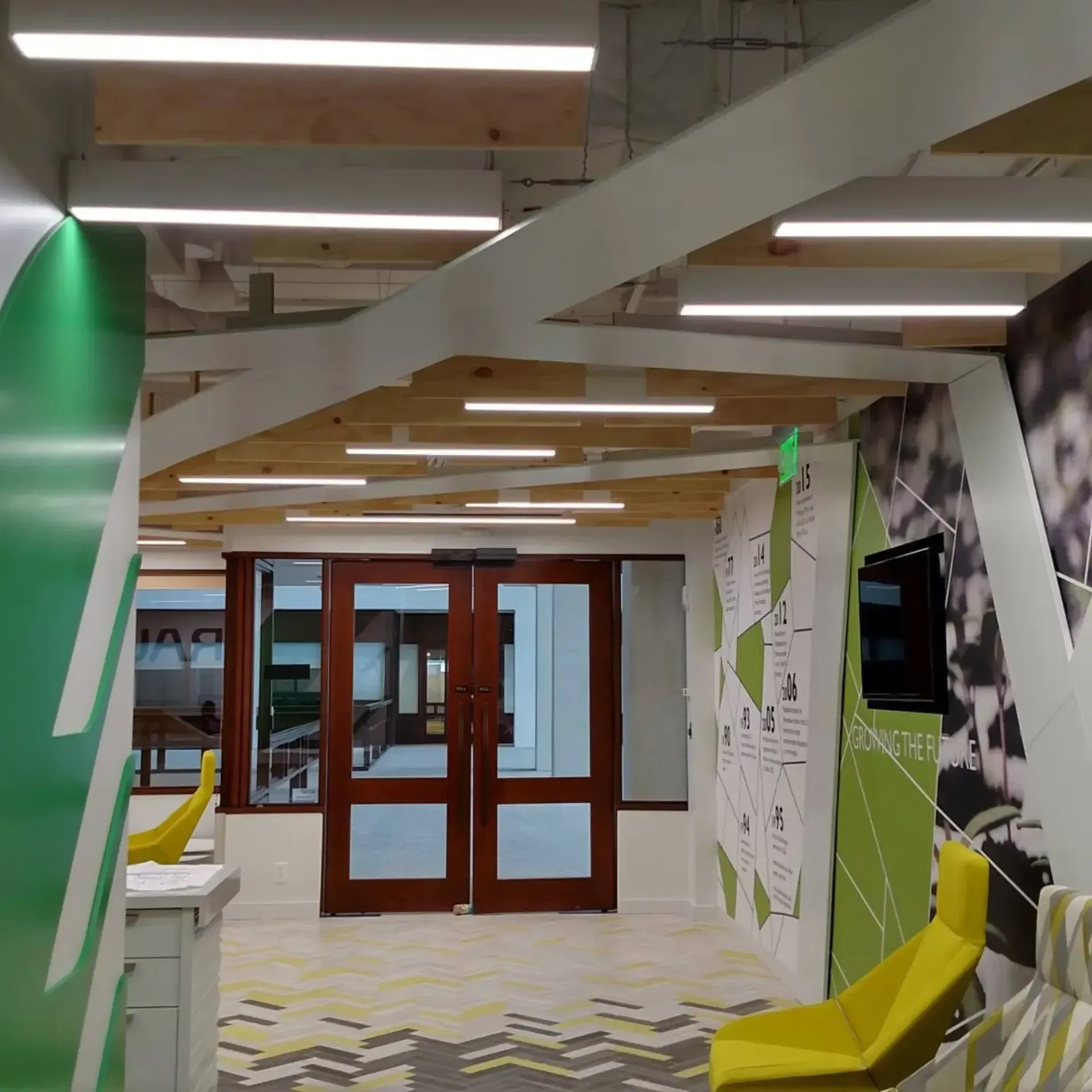 Interior hallway with wooden doors and abstract, tree-like wall design, and yellow seating