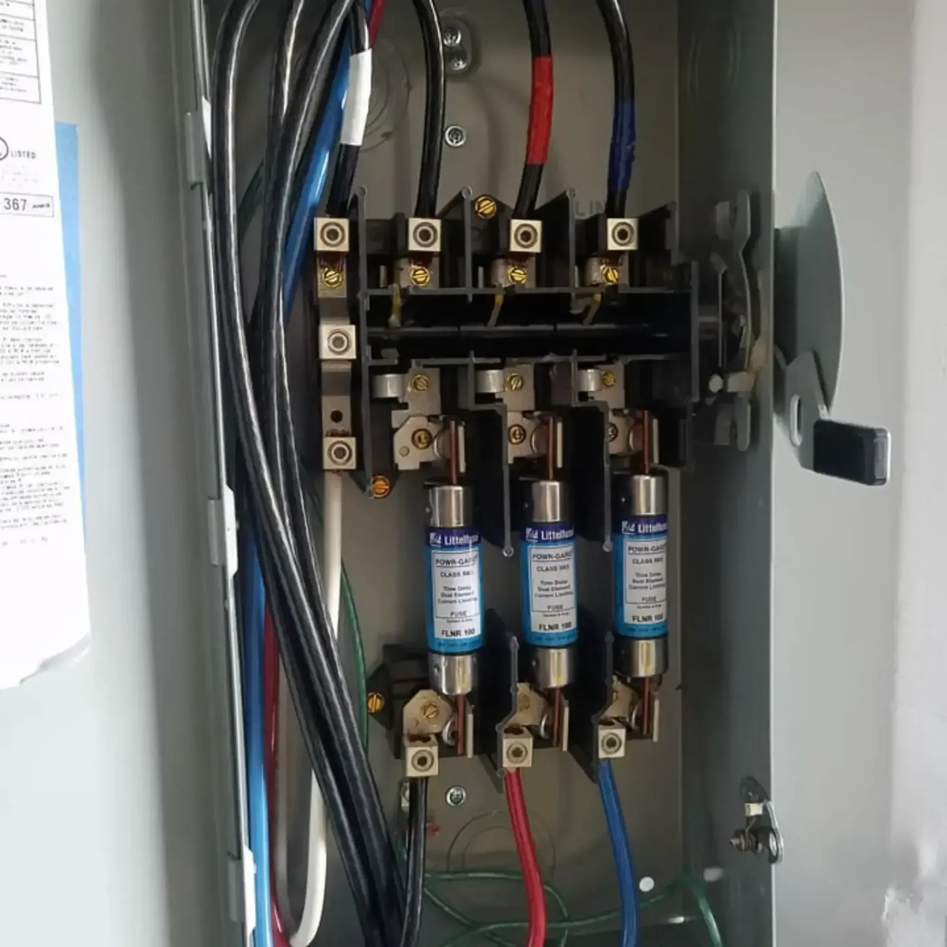 Electrical panel with three blue fuses, wires, and a handle