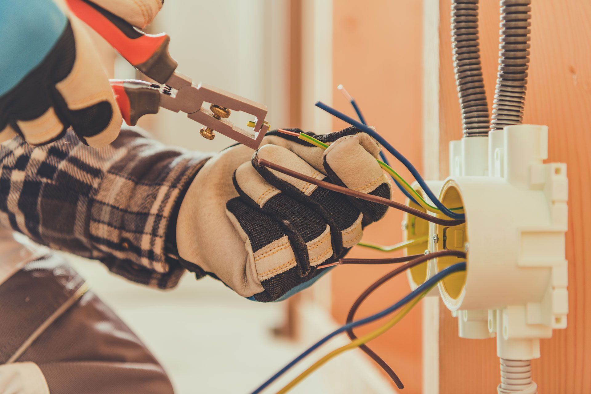 A person in a plaid shirt flips a breaker switch in a gray electrical service panel.