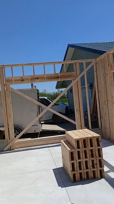 Wooden construction framing and stacked cinder blocks on a concrete slab under a clear blue sky