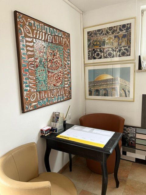 Ein Raum mit einem Stuhl, einem Tisch und einem Gemälde an der Wand