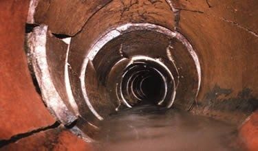 Circular tunnel with concentric rings and reddish-brown walls, receding into darkness.
