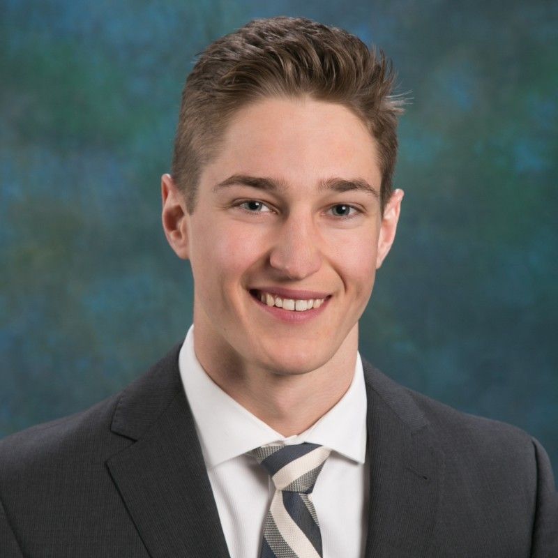 A young man in a suit and tie smiles for the camera