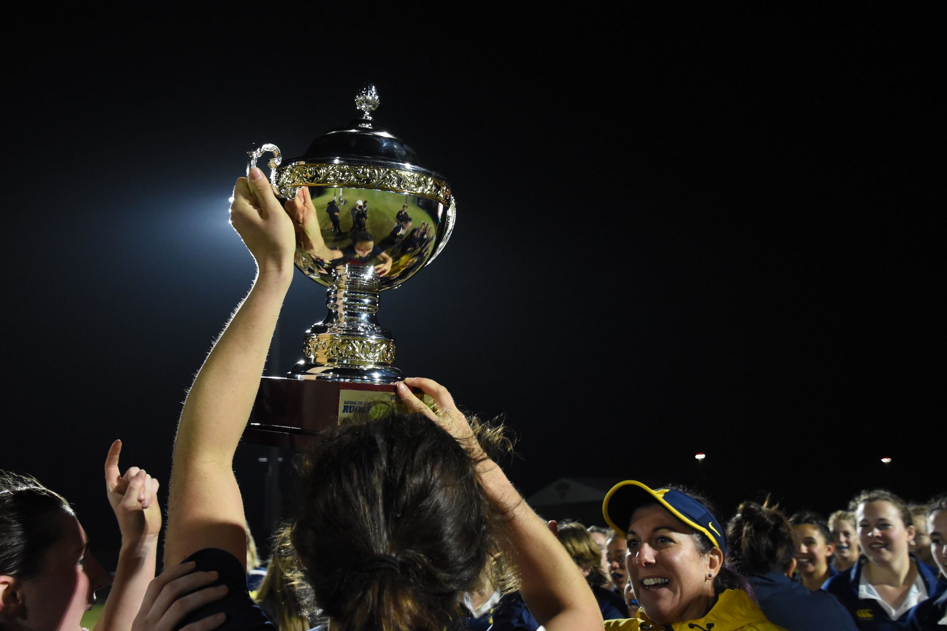 A group of people are holding a trophy in the air.