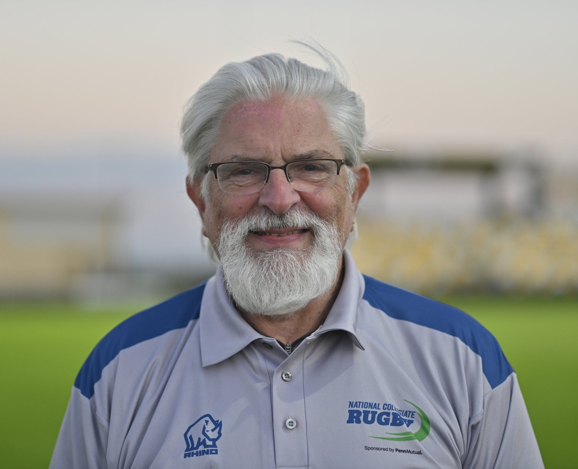 A man with a beard and glasses is wearing a rugby shirt