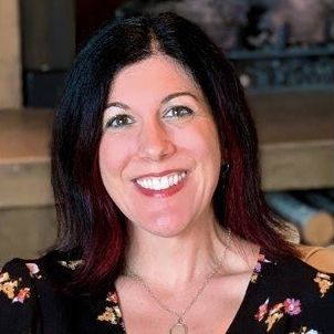 A woman with dark hair and red highlights is smiling for the camera.