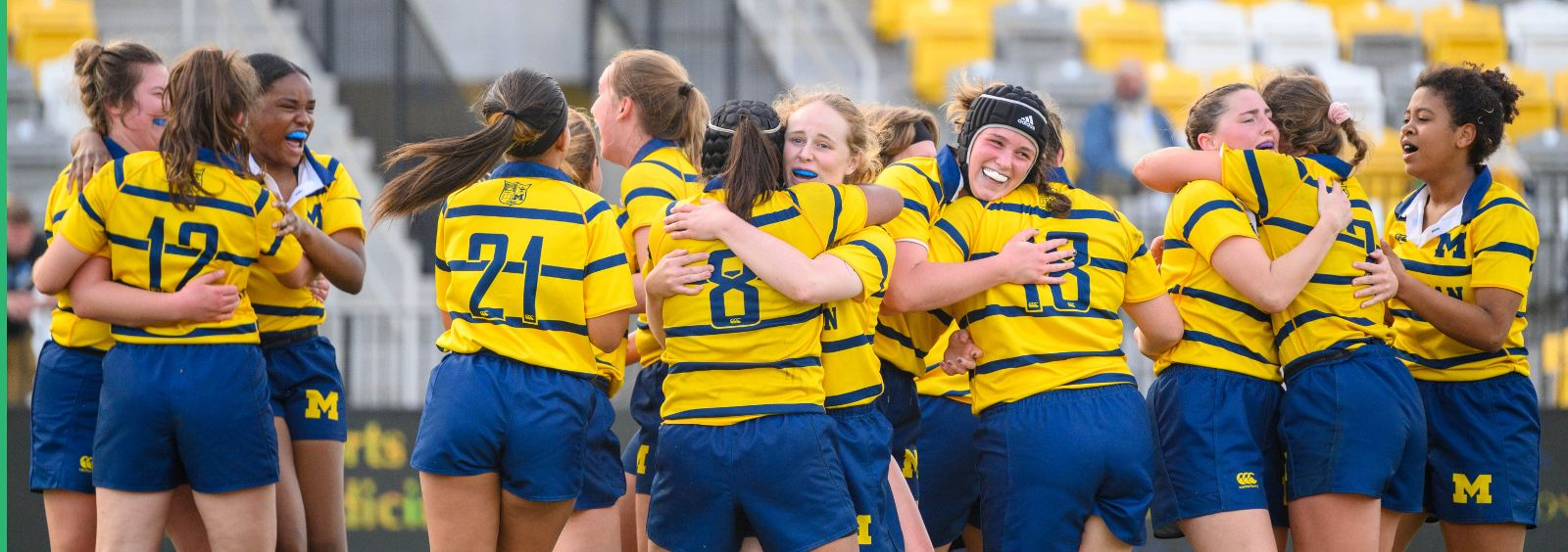 A group of female soccer players are hugging each other on a field.