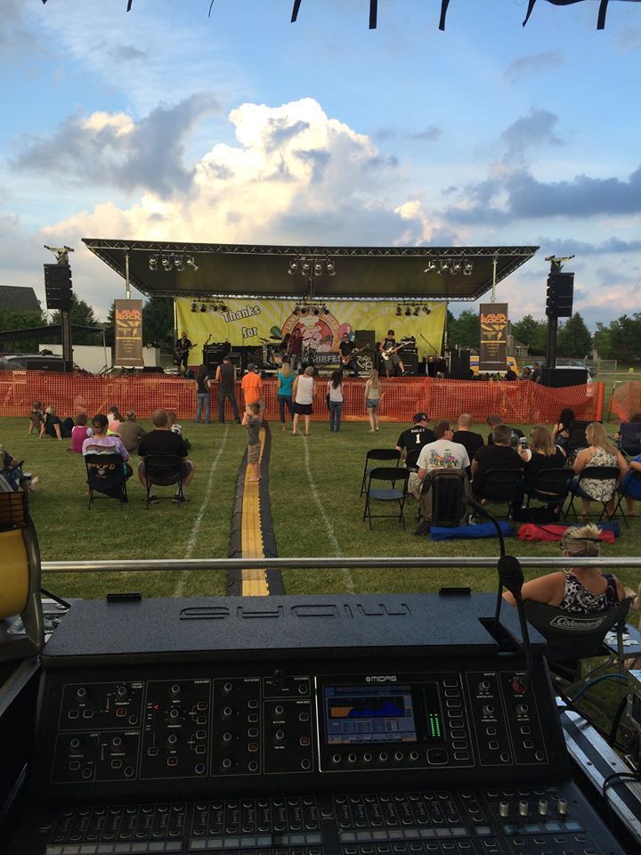 A group of people are sitting in front of a stage at a concert.