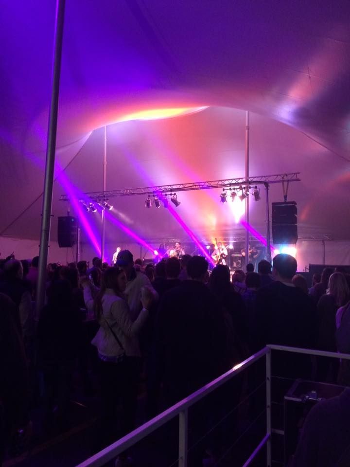 A crowd of people are gathered under a tent at a concert.
