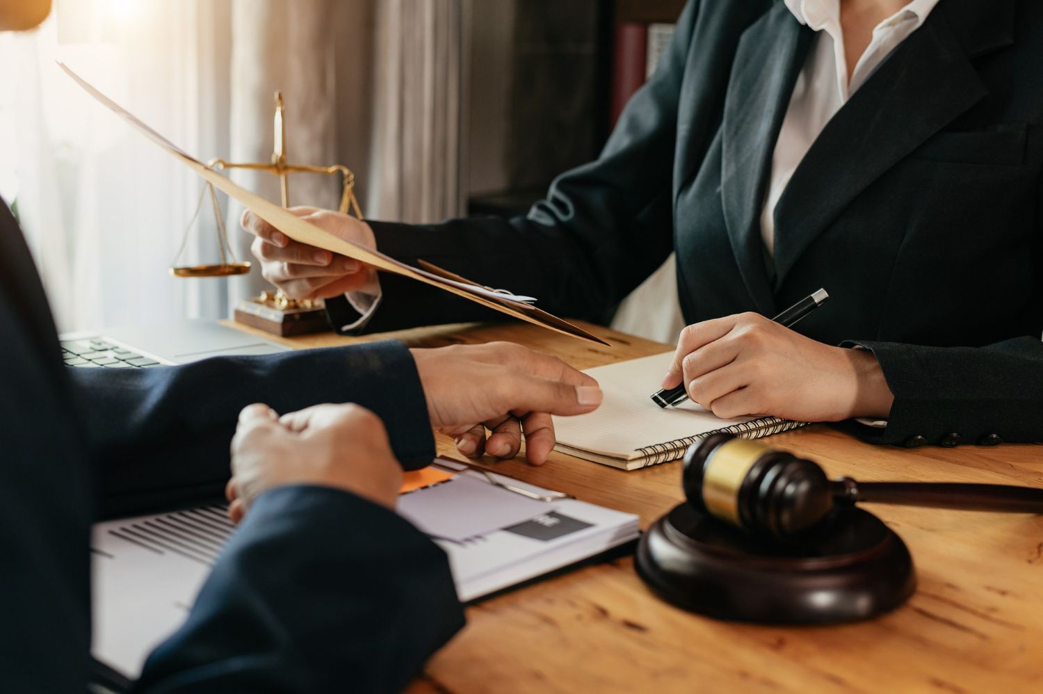 Lawyers signing a document at a desk with a gavel in the foreground