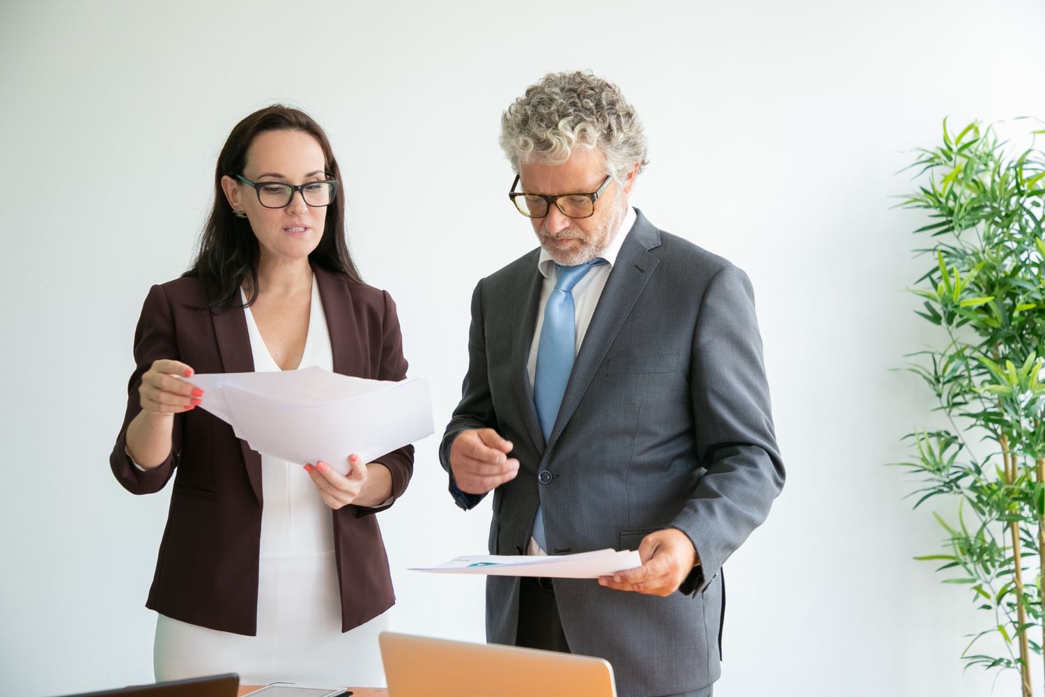 Two professionals in business attire reviewing documents in a bright office