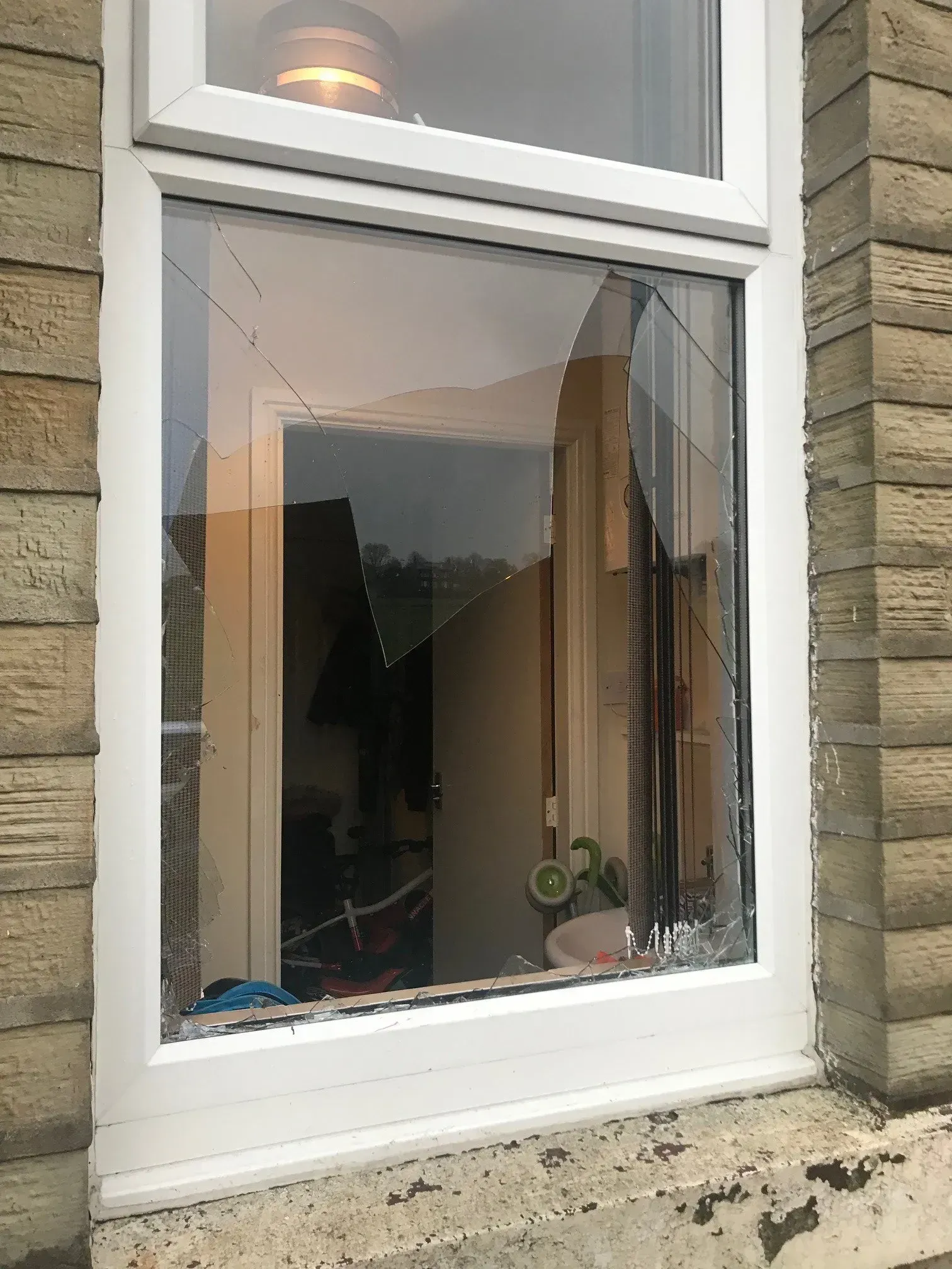 Broken window in a white frame, with shattered glass.