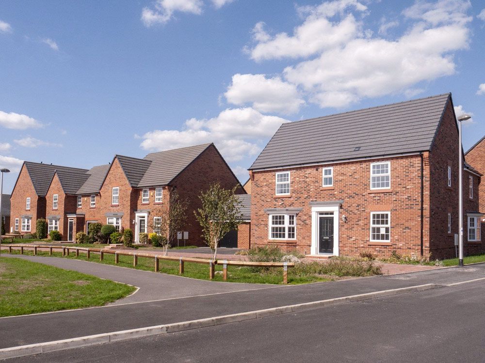 Row of red brick houses with gray roofs on a sunny day.