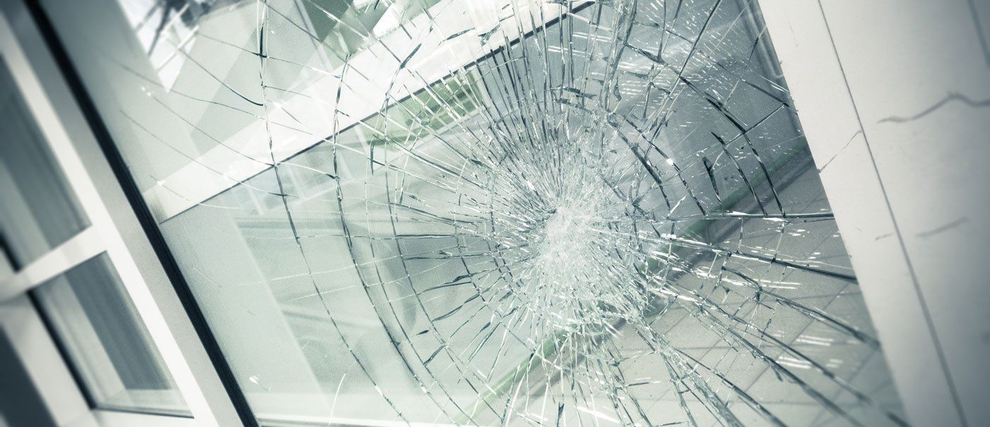 Broken glass window with cracks radiating from a central point. Window frame in view.