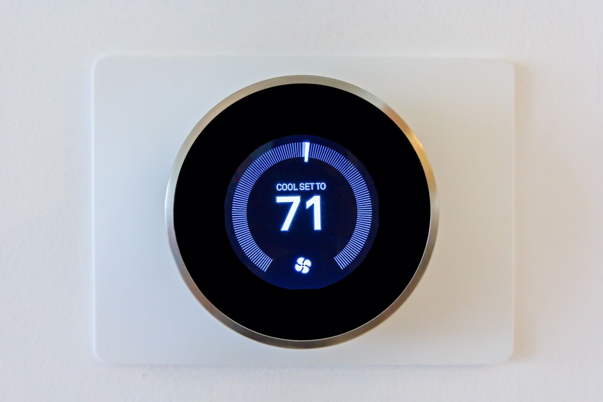 Digital thermostat displaying 71 degrees Fahrenheit, set on a white wall.
