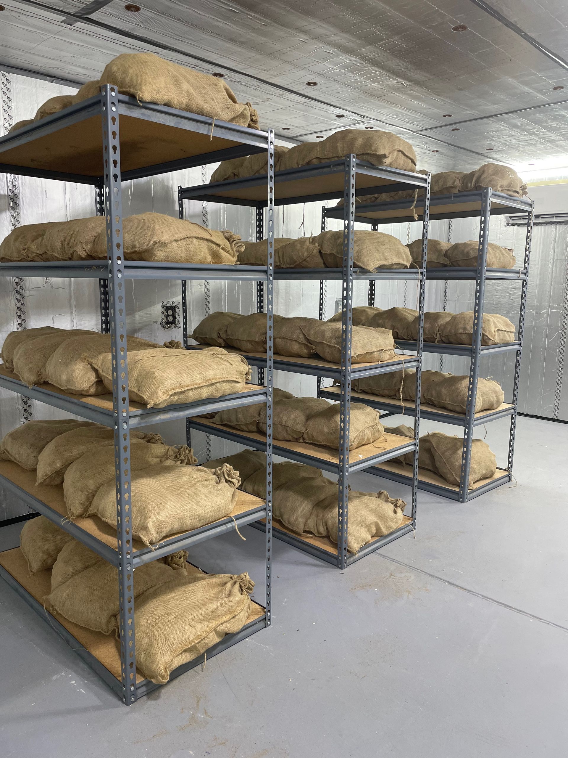 Rows of organic garlic stored in burlap bags in storage facility