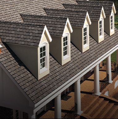 Roof of a house with dormer windows, brown shingles, and columns.