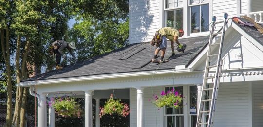 Person installing shingles on roof