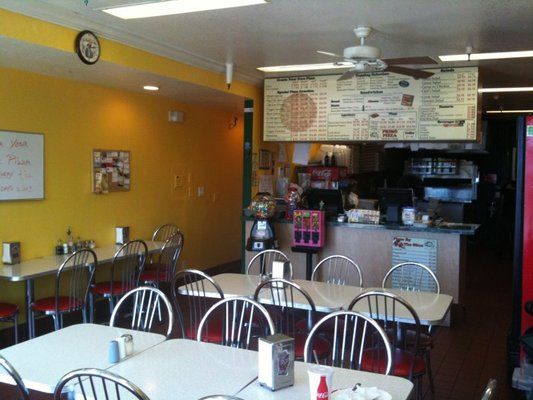 A restaurant with tables and chairs and a menu on the wall