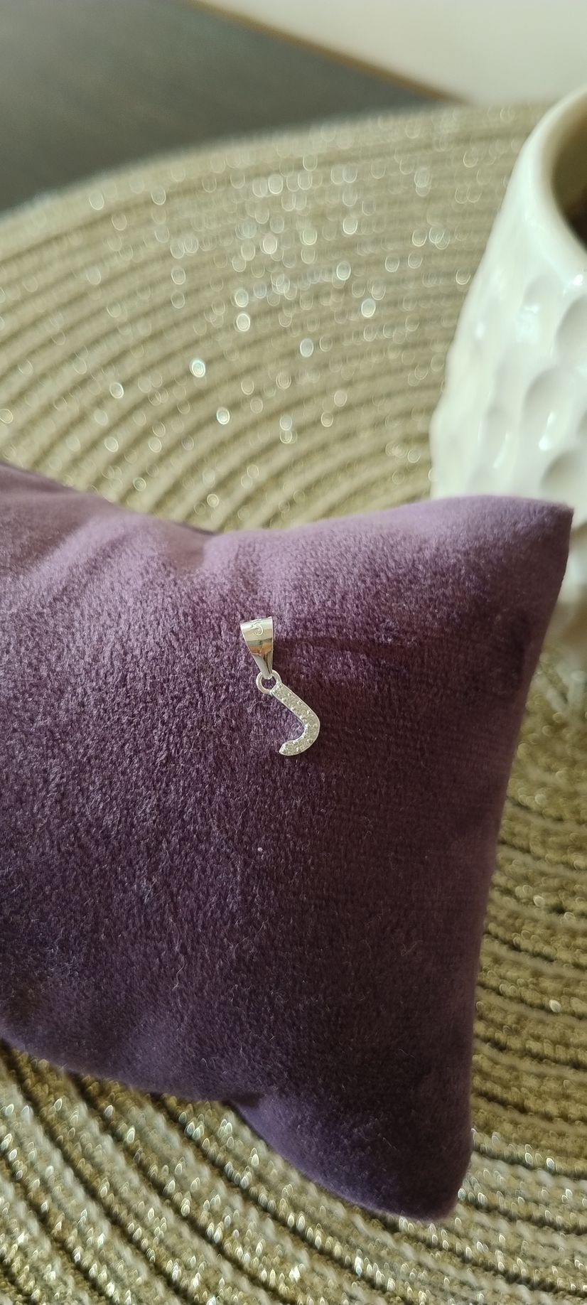 Un colgante de plata con forma de letra 