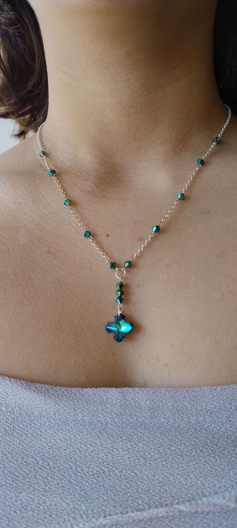 Persona que lleva un collar de plata con cristales de color verde azulado.