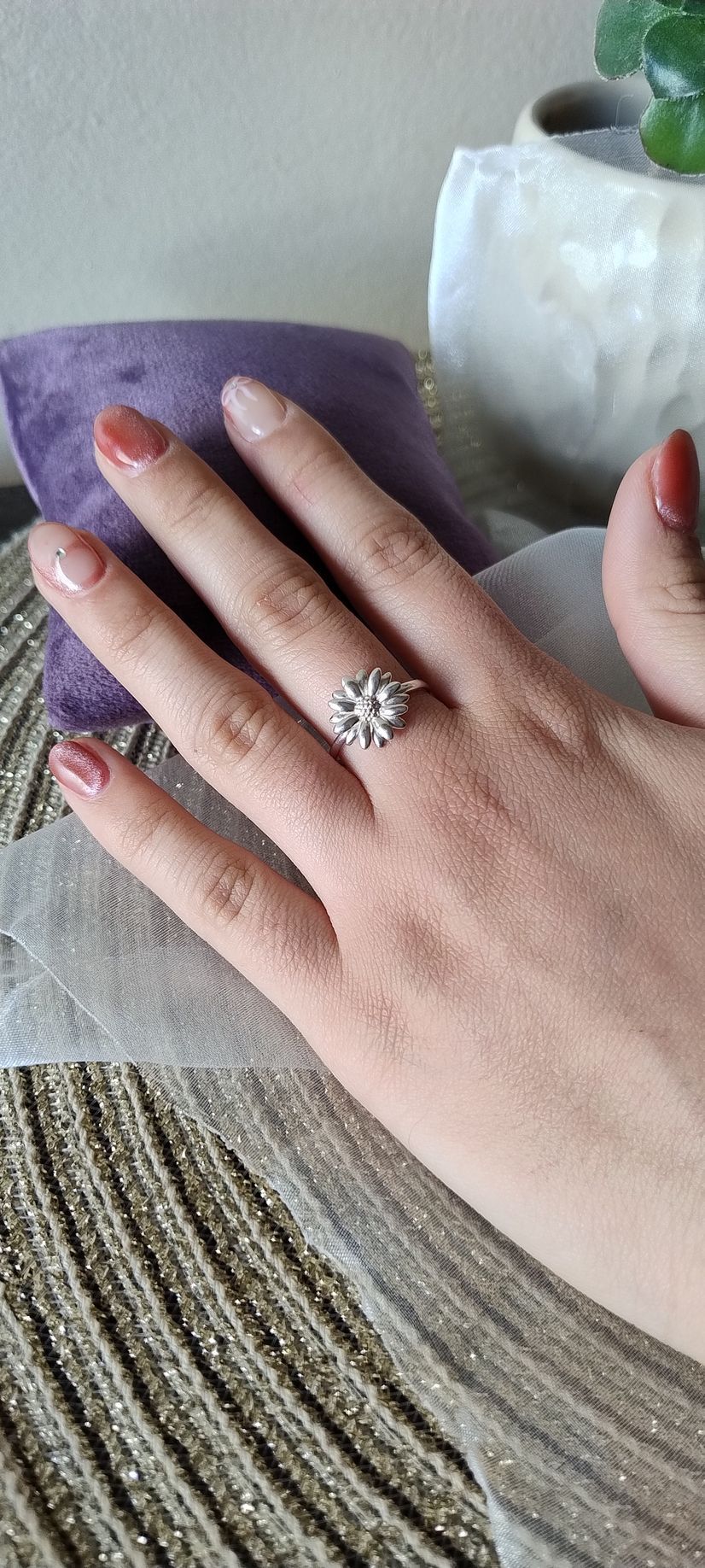 Mano con un anillo de copo de nieve, apoyada sobre una tela con un paño morado.