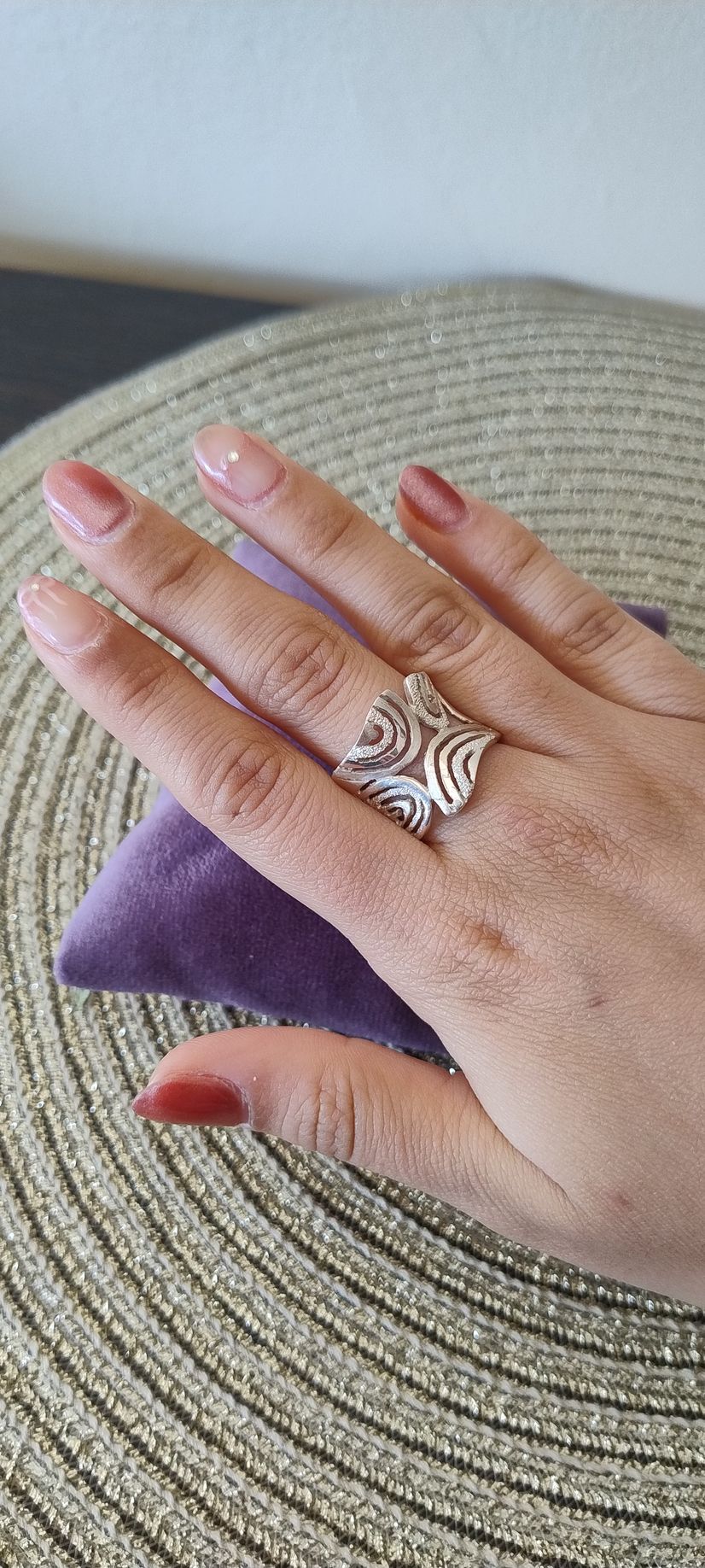Mano con un anillo de plata sobre una superficie de terciopelo púrpura.