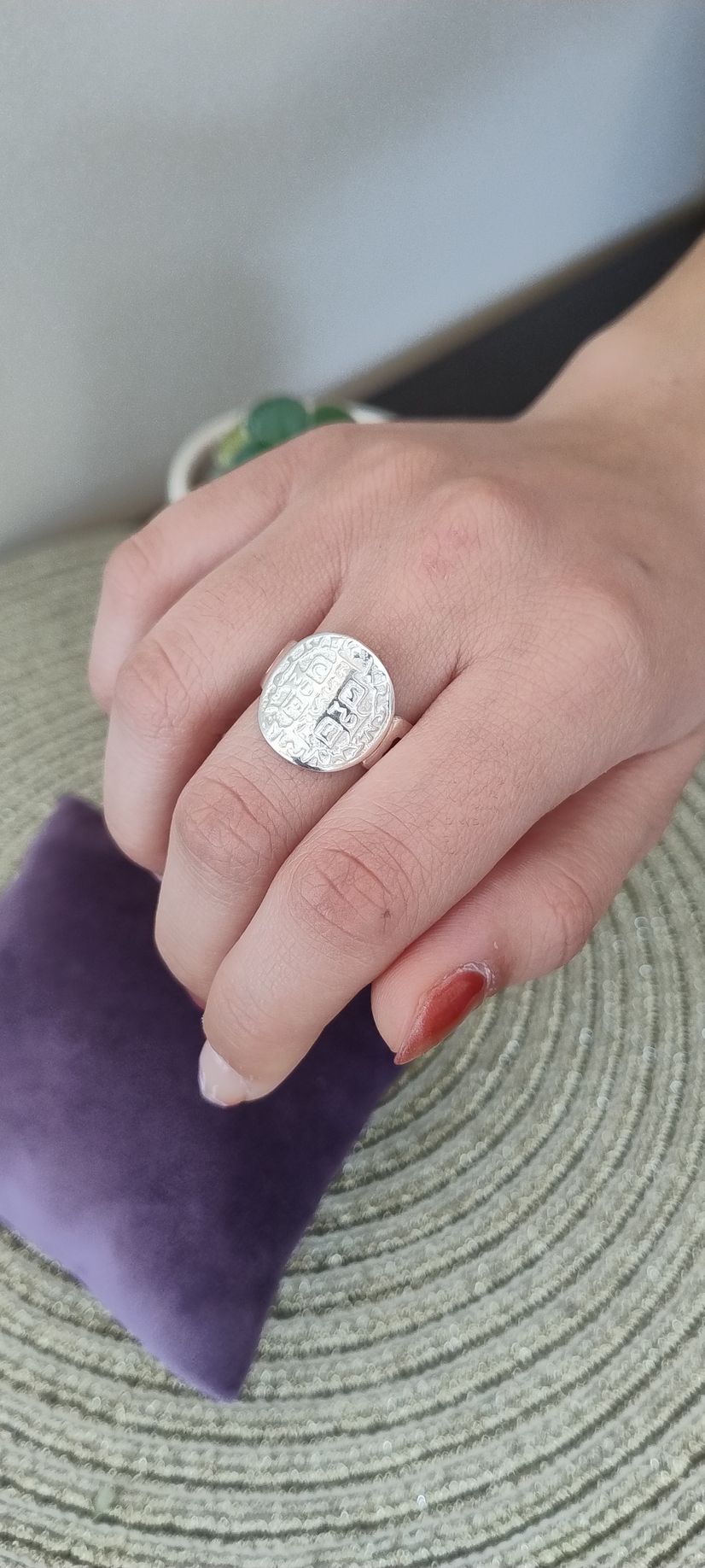 Una mano que luce un gran anillo brillante descansa sobre una superficie de terciopelo púrpura.