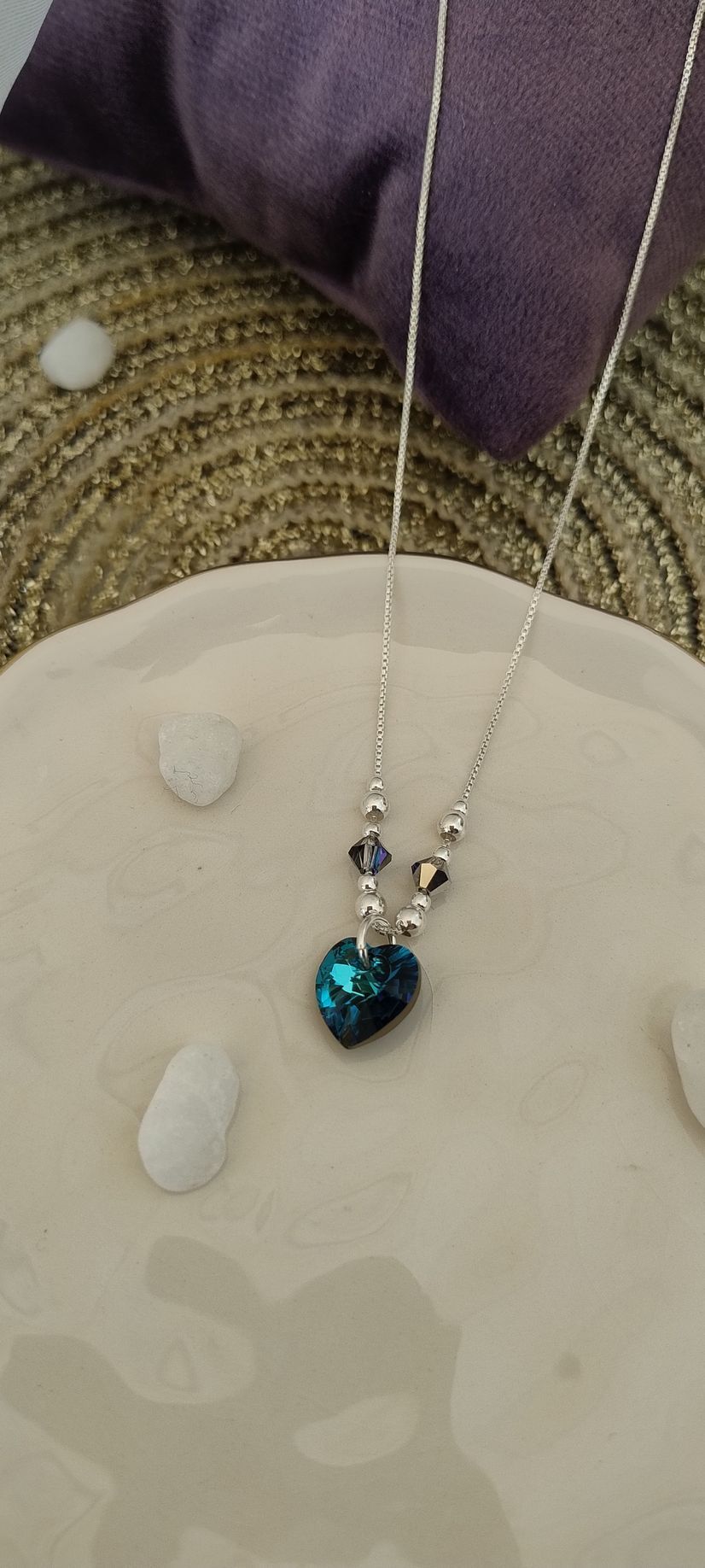 Collar de plata con un colgante azul sobre una blusa plateada brillante con escote en V.
