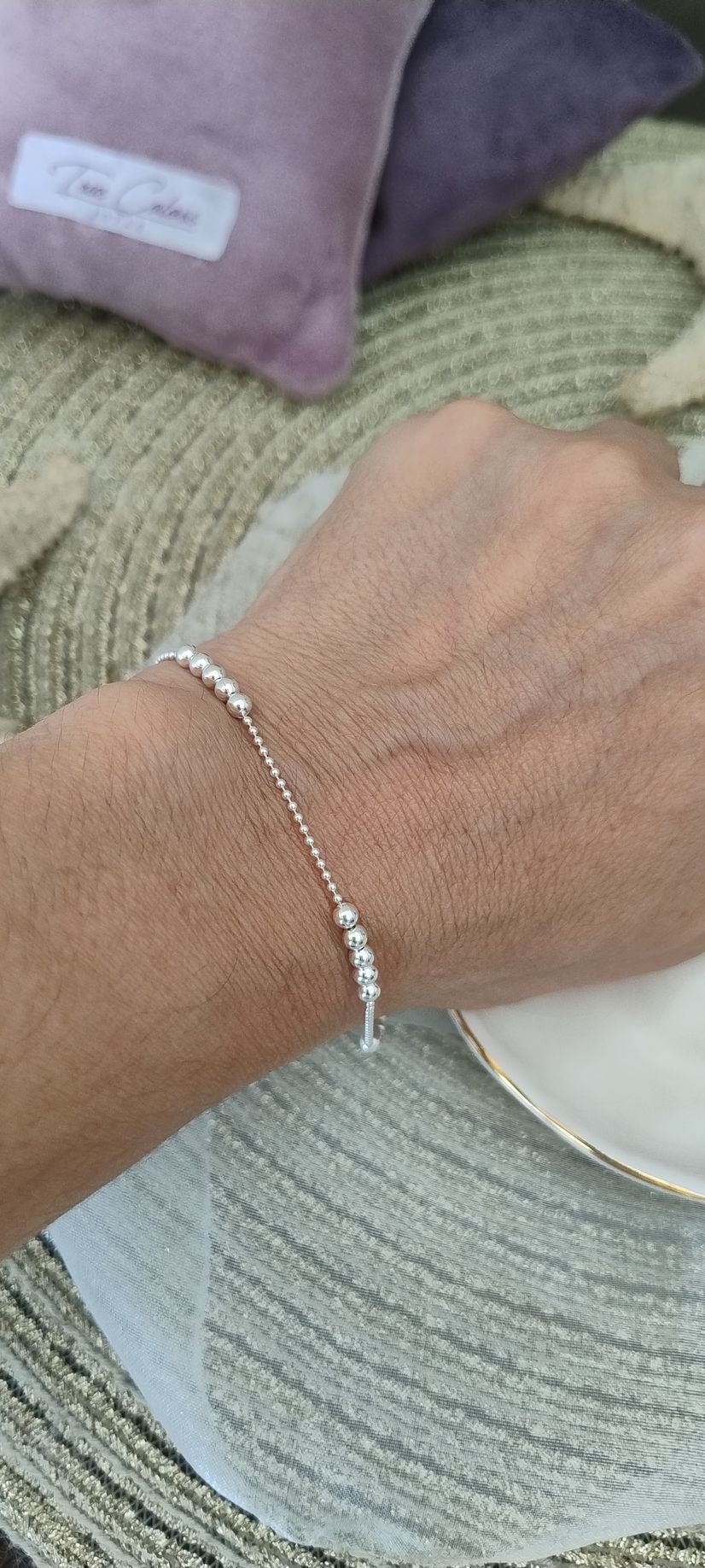 Muñeca con pulsera alzada contra un soleado paisaje exterior con árboles y cielo azul.