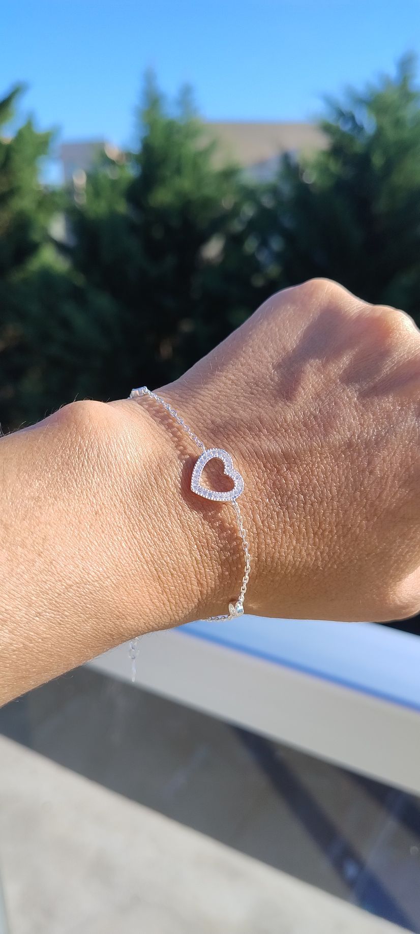 Primer plano de una mano al aire libre con una pequeña lesión cutánea redonda o un vendaje en la muñeca.