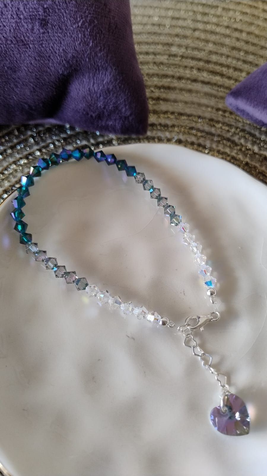 Pulsera de cuentas sobre una base blanca. Cuentas con degradado de azul a transparente y un colgante en forma de corazón.