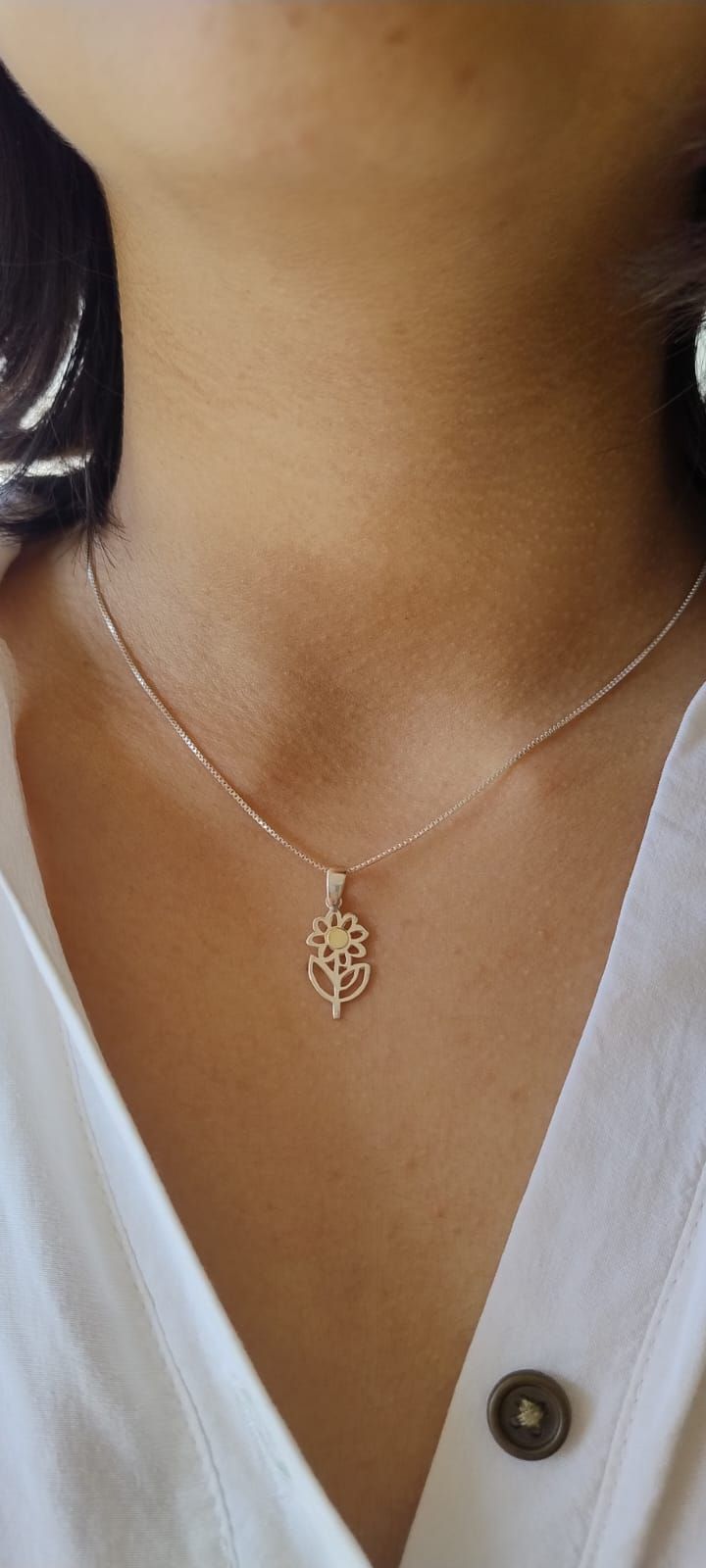 Una persona que lleva un collar de cadena plateada con un colgante dorado en forma de símbolo de dólar.