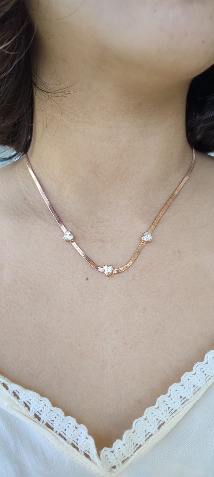 Una persona que lleva un collar de oro rosa con colgantes en forma de corazón.