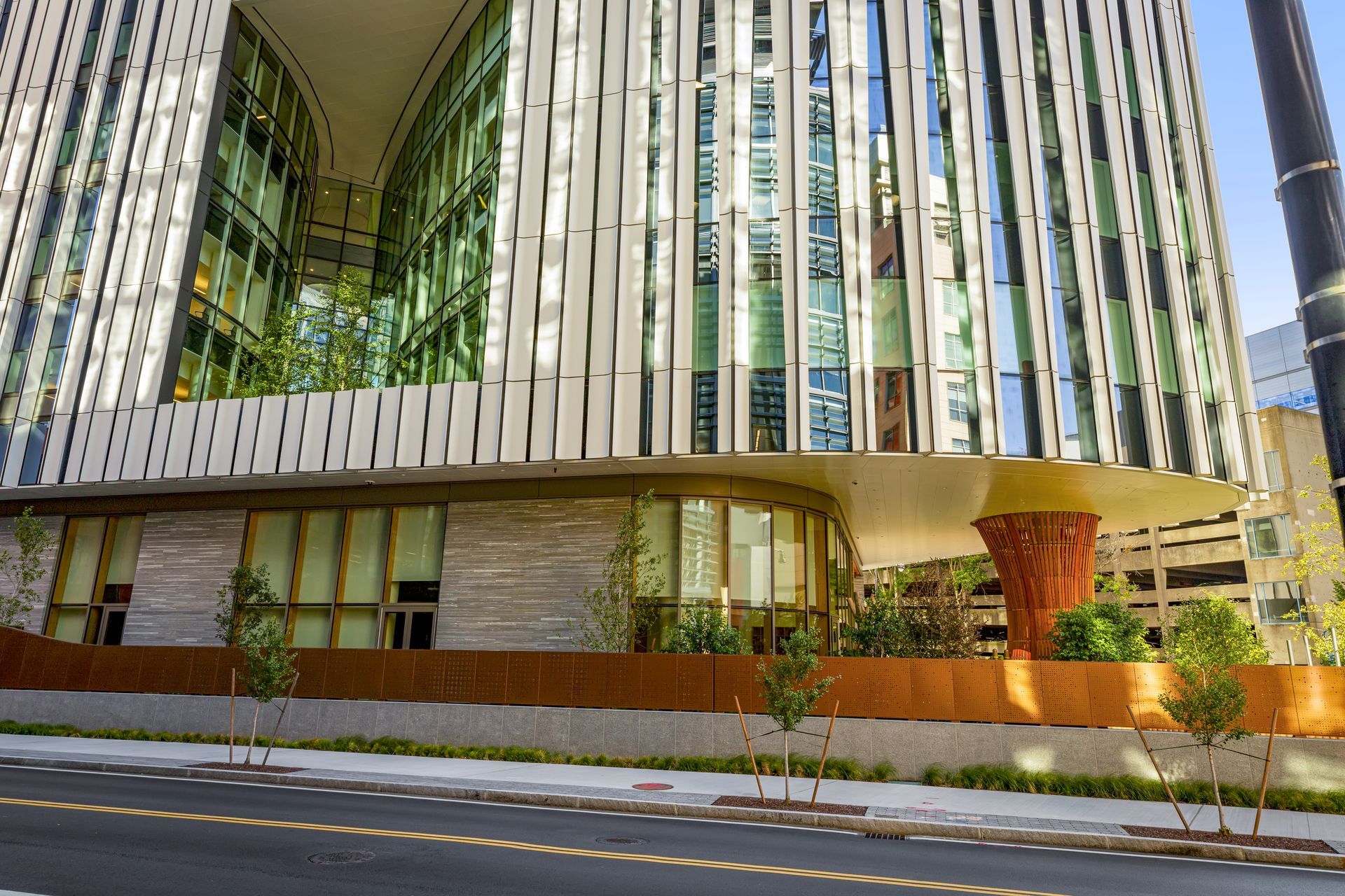 Modern building with white vertical accents, curved glass, and a decorative copper-colored column.